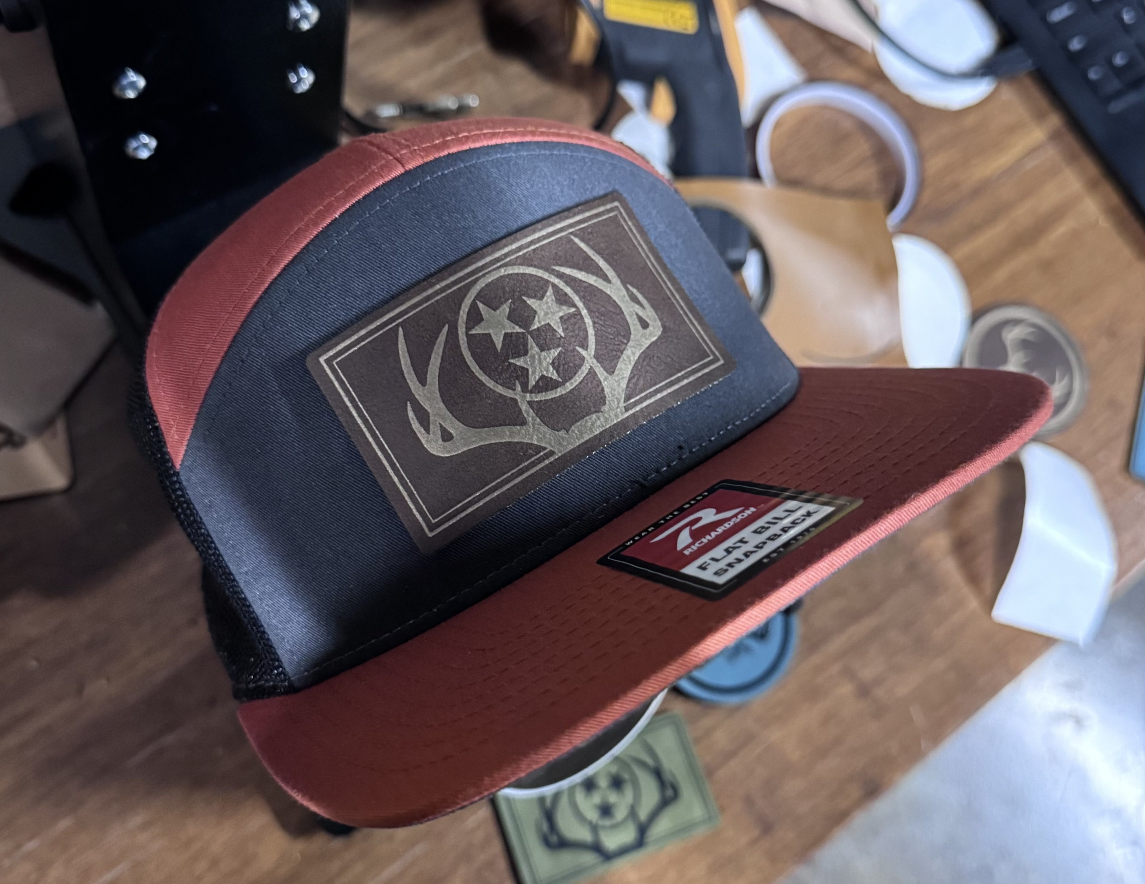 Richardson 168 - 7 Panel Trucker Hat – Charcoal/Burnt Orange/Black - Custom Leatherette Patch w Your Logo